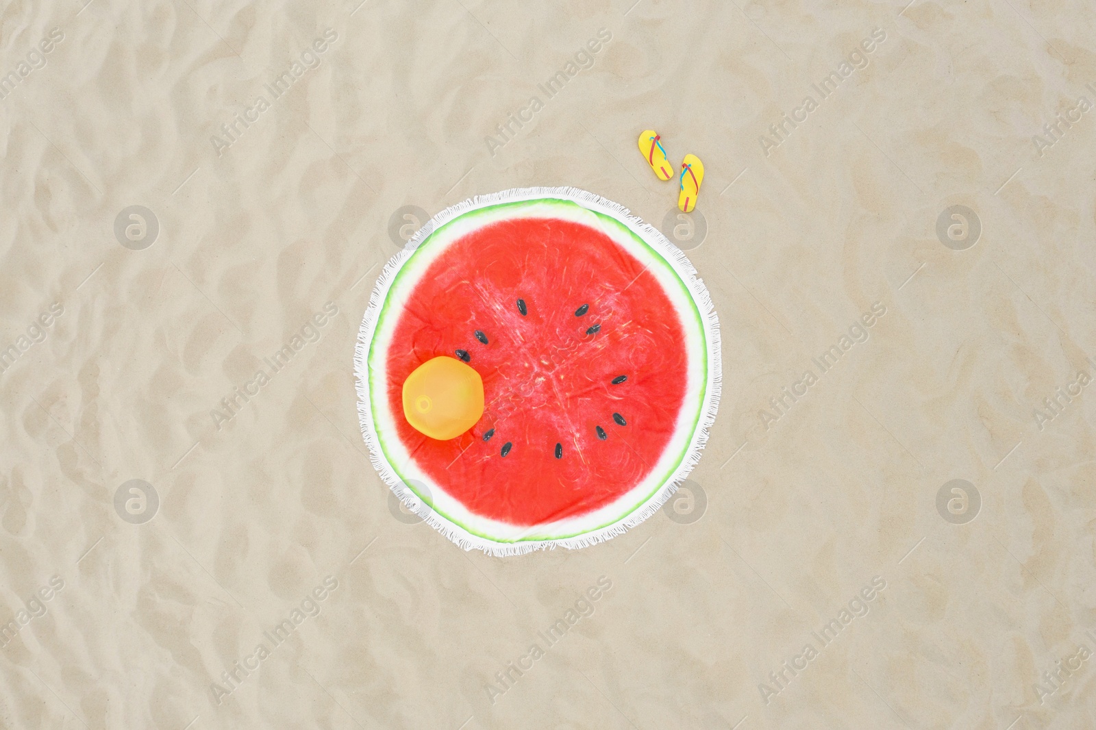 Image of Round watermelon beach towel, ball and flip flops on sand, aerial view