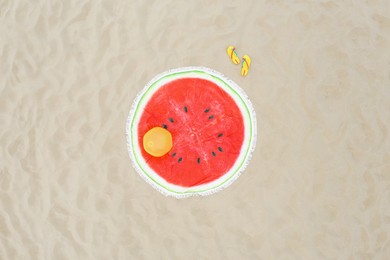Round watermelon beach towel, ball and flip flops on sand, aerial view
