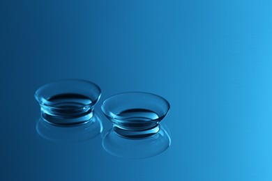 Pair of contact lenses on mirror surface, toned in blue. Space for text