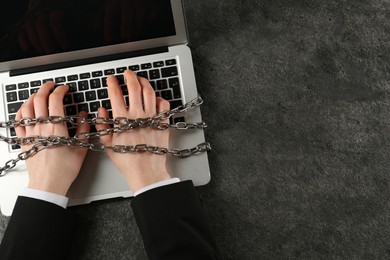Photo of Man chained to laptop at grey table, top view and space for text. Internet addiction