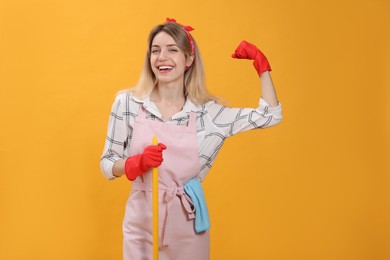 Photo of Young housewife with broom on yellow background