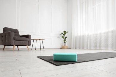 Exercise mat and yoga block indoors, low angle view