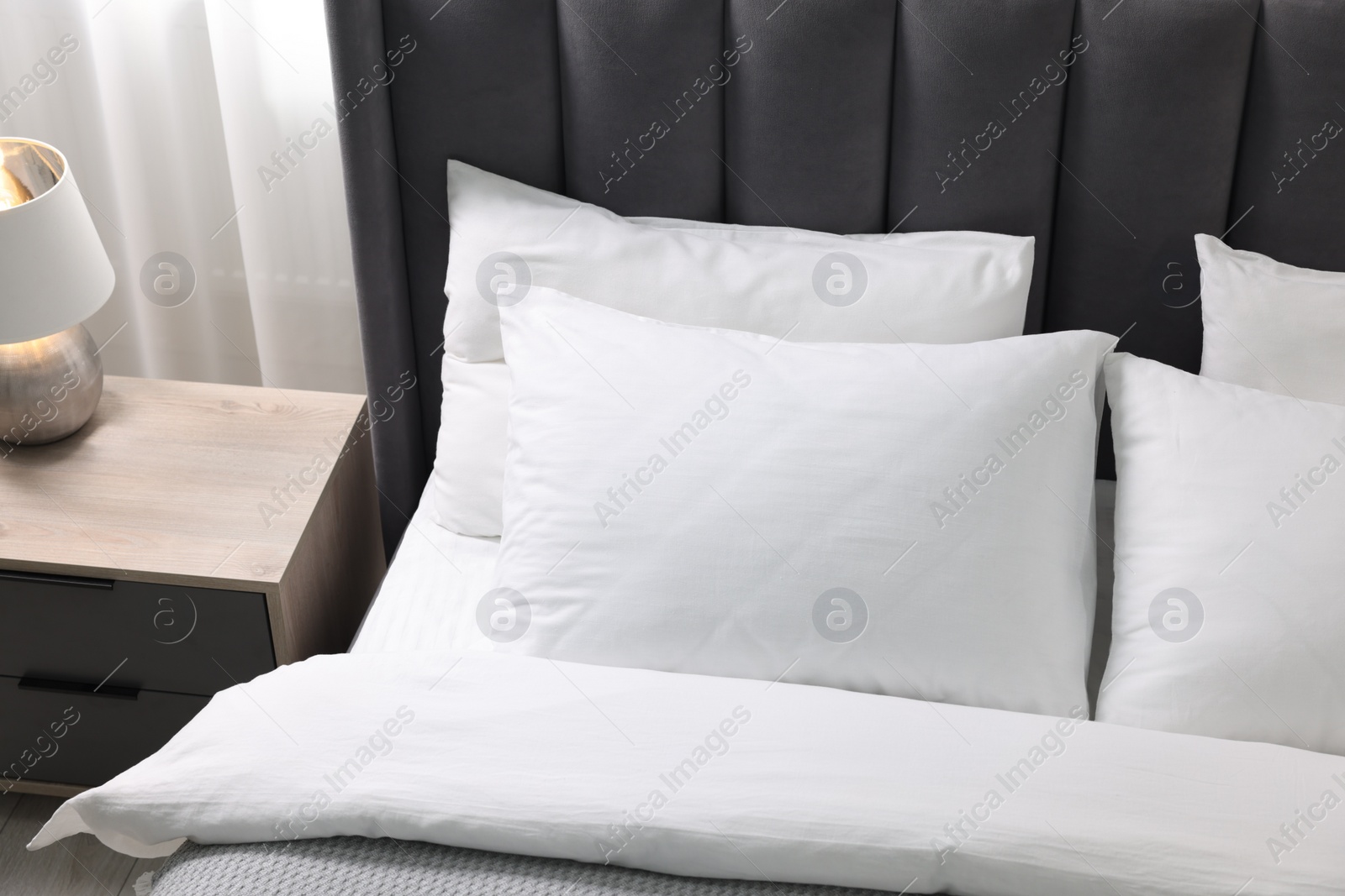 Photo of Soft white pillows and duvet on bed at home