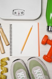 Photo of Notebook, scales and sports equipment on white wooden table, flat lay. Personal training
