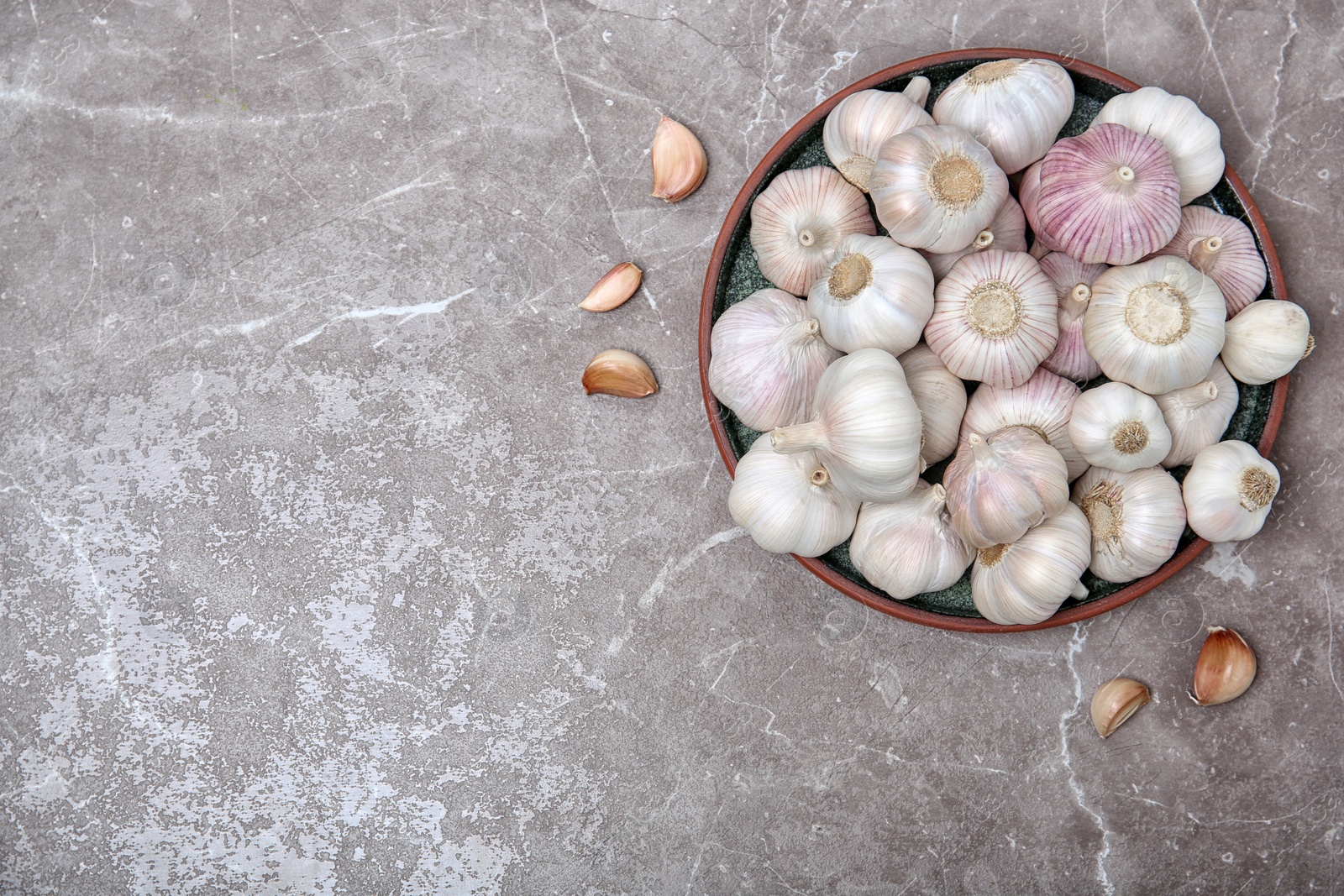 Photo of Bowl with garlic on grey background, top view