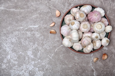 Bowl with garlic on grey background, top view