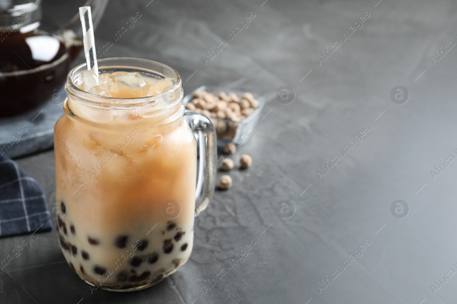 Photo of Tasty brown milk bubble tea on grey table, closeup. Space for text