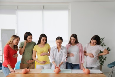 Photo of Pregnant women learning how to swaddle baby at courses for expectant mothers indoors