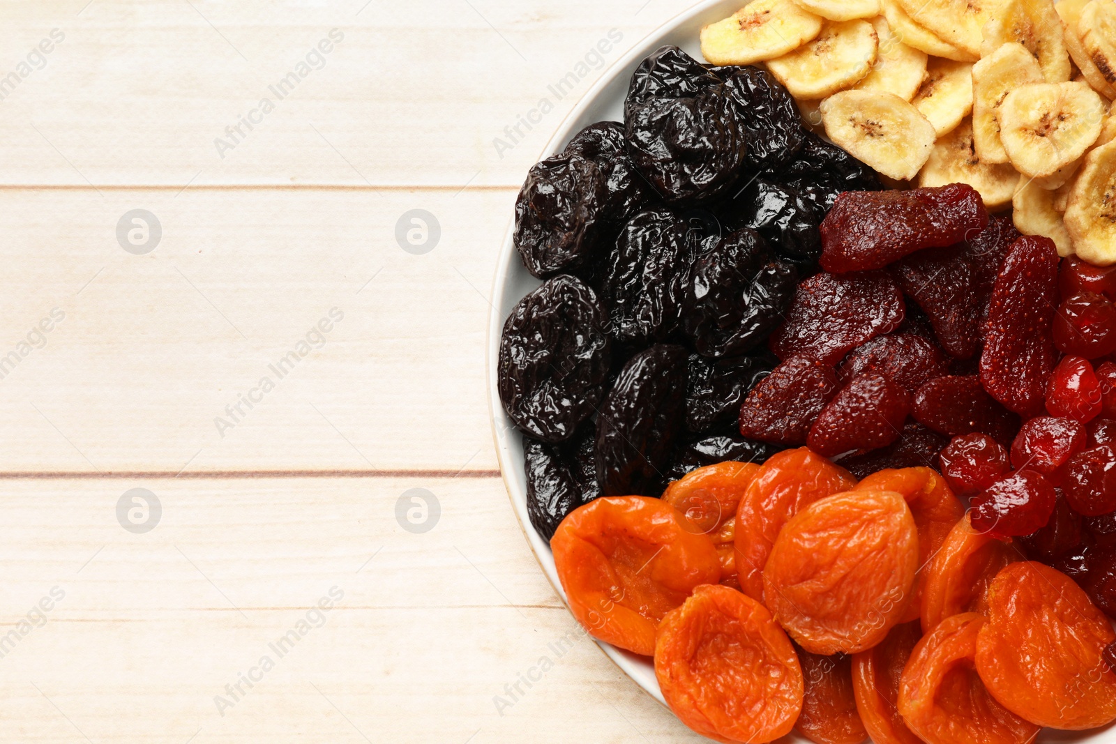 Photo of Delicious dried fruits on white wooden table, top view. Space for text