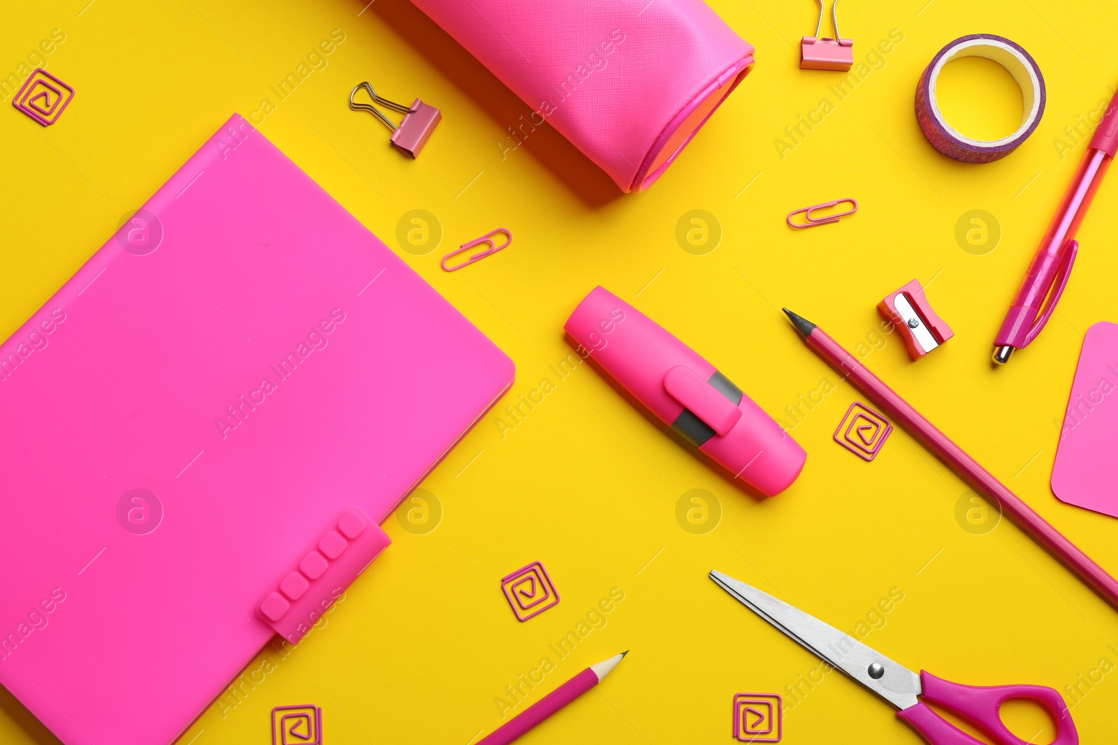 Photo of Pink school stationery on yellow background, flat lay