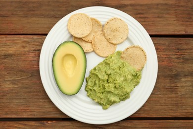 Delicious guacamole, avocado and chips on wooden table, top view