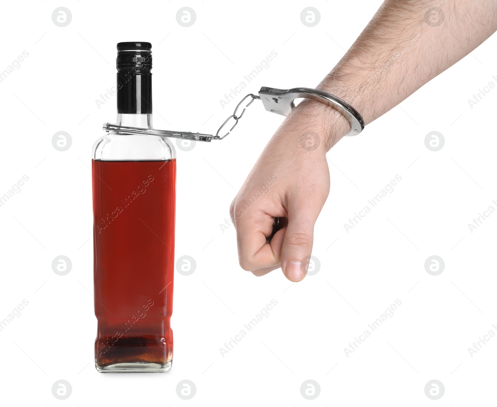 Photo of Addicted man in handcuffs with bottle of alcoholic drink on white background, closeup