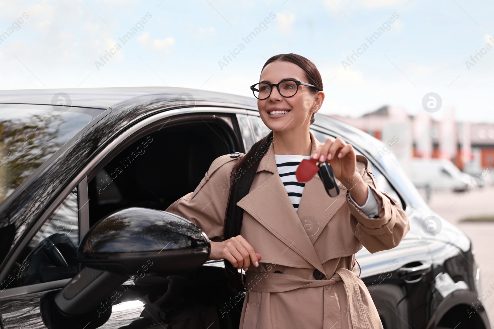 Photo of Woman holding car flip key near her vehicle outdoors