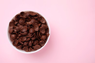 Photo of Breakfast cereal. Chocolate corn flakes in bowl on pink table, top view. Space for text