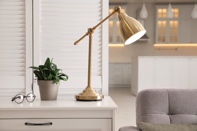 Photo of Stylish lamp on chest of drawers in room