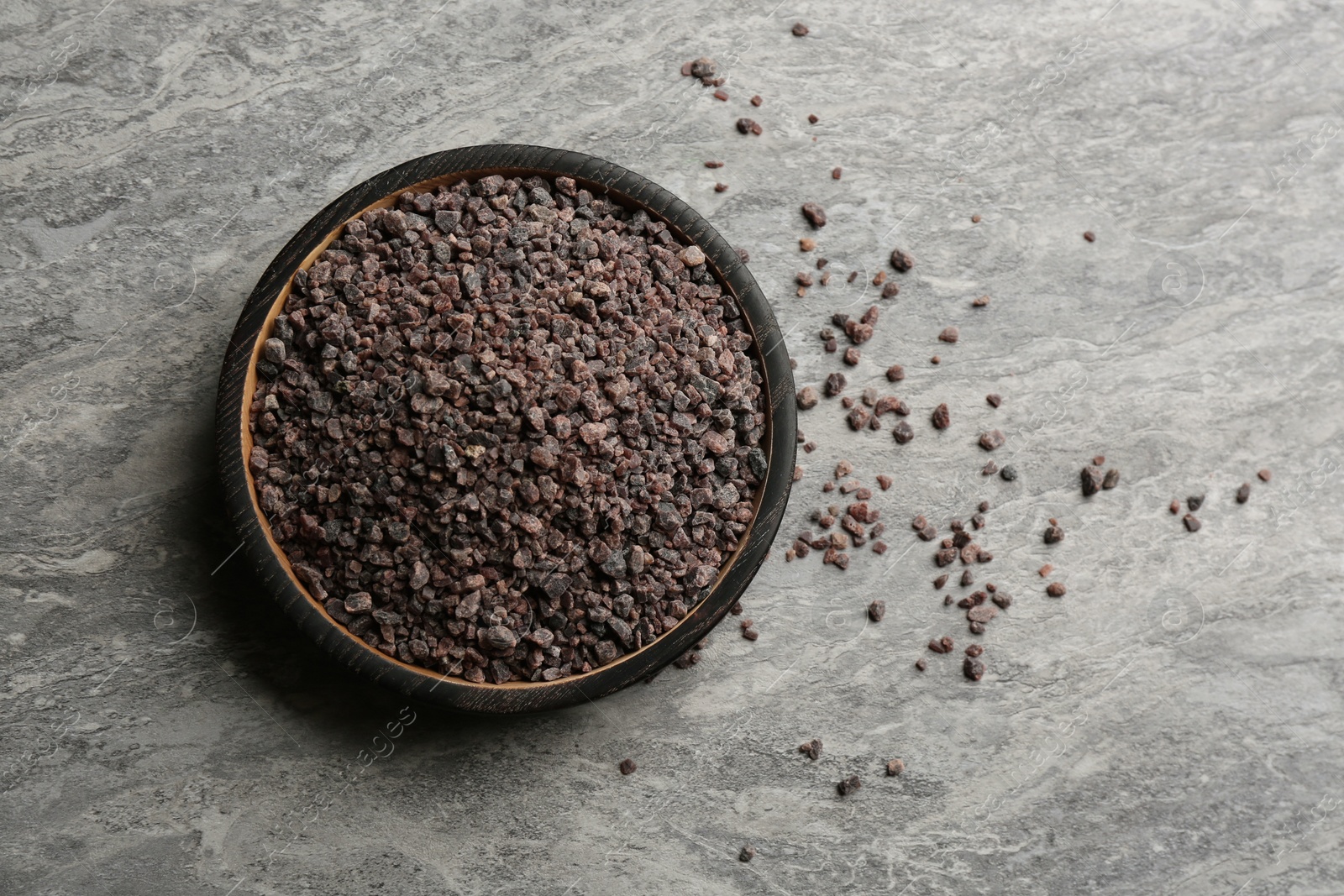 Photo of Black salt on grey table, top view. Space for text