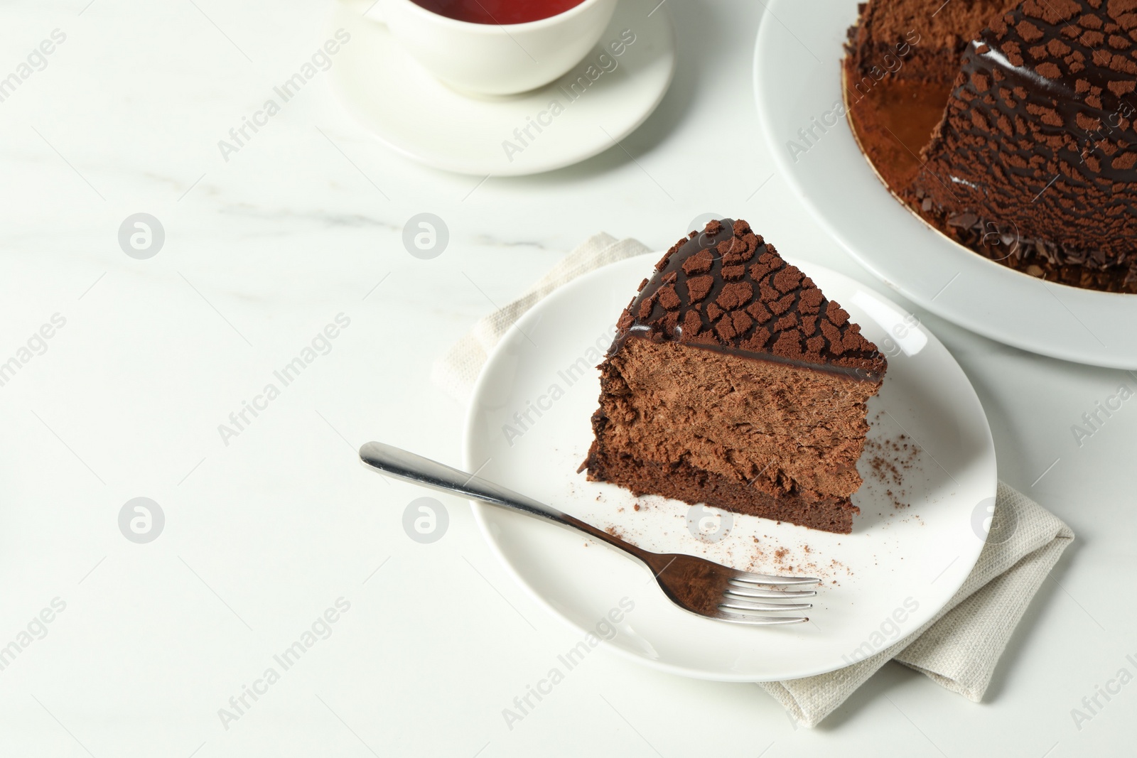 Photo of Piece of delicious chocolate truffle cake on white marble table, space for text