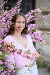 Beautiful young woman near blossoming sakura tree on spring day
