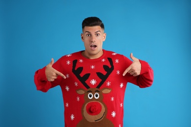 Surprised man pointing on his Christmas sweater against blue background