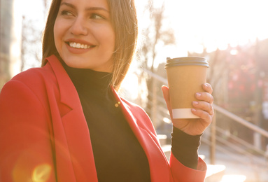 Photo of Businesswoman with cup of coffee on city street in morning