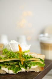 Delicious sandwich with vegetables and poached egg on board, closeup. Space for text