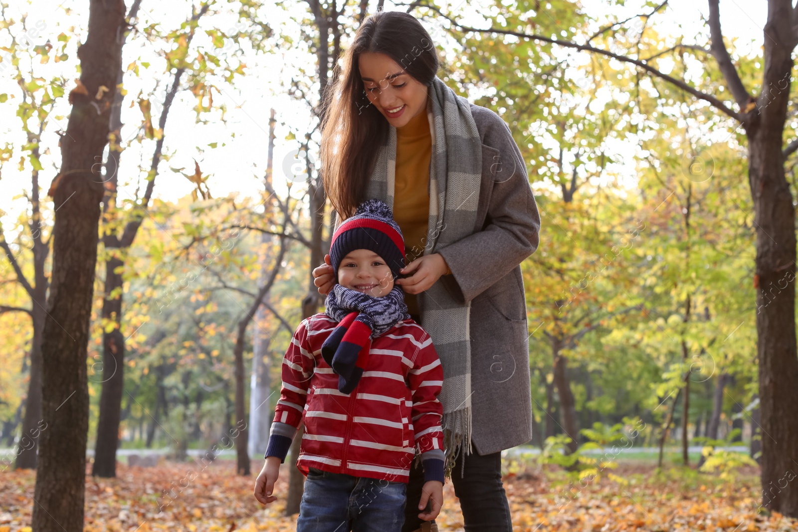 Photo of Mother with her cute son spending time together in park. Autumn walk