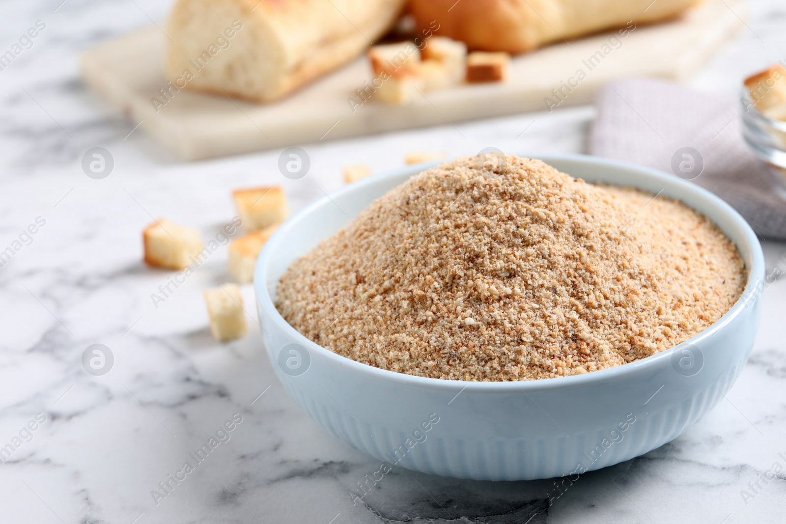 Photo of Fresh breadcrumbs in bowl on white marble table