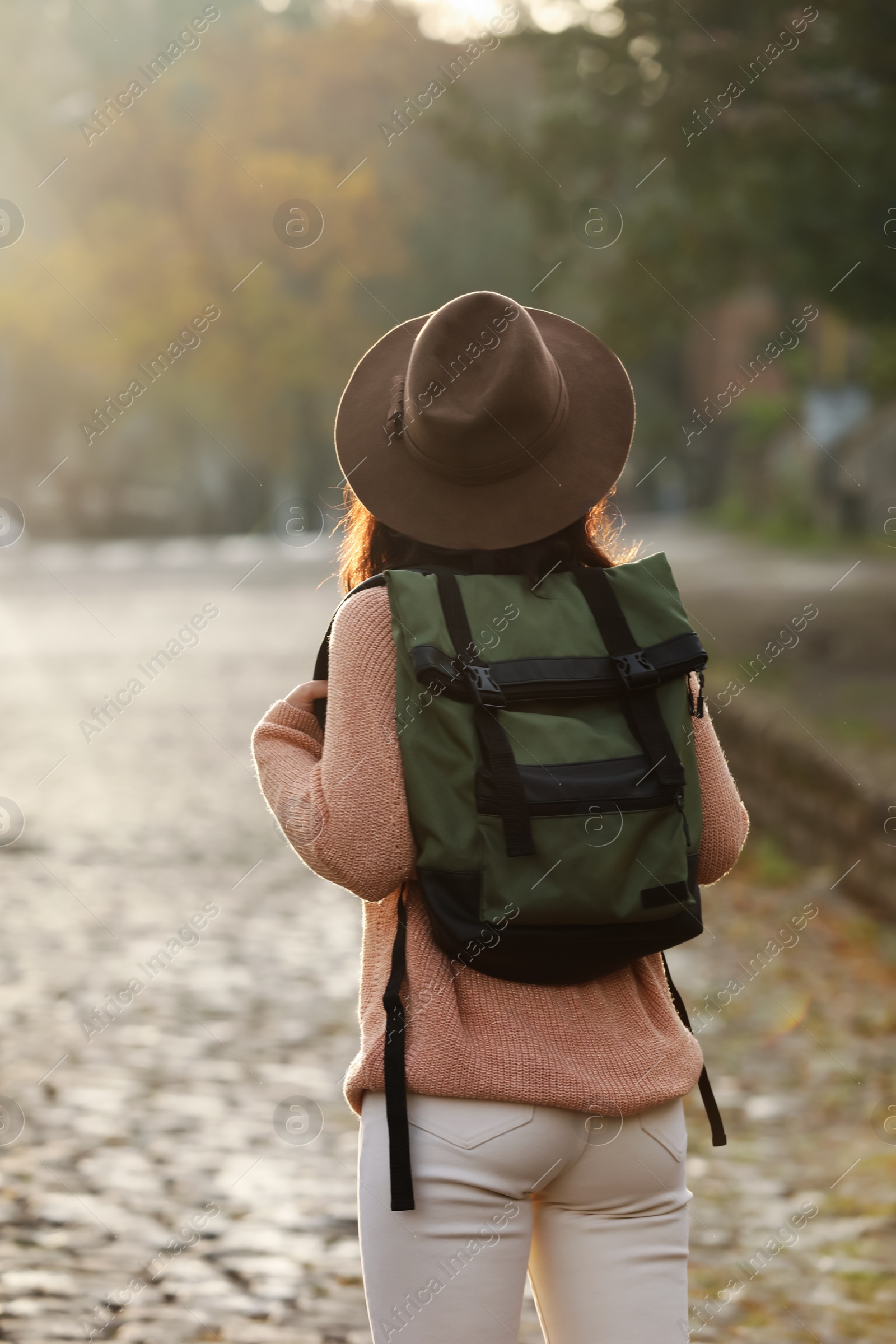 Photo of Traveler with backpack on city street, back view