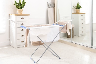 Clean laundry hanging on drying rack indoors