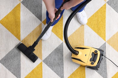 Photo of Dry cleaner's employee hoovering carpet with vacuum cleaner, above view