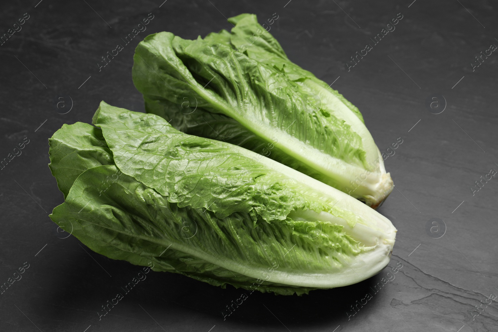 Photo of Fresh green romaine lettuces on black table, closeup