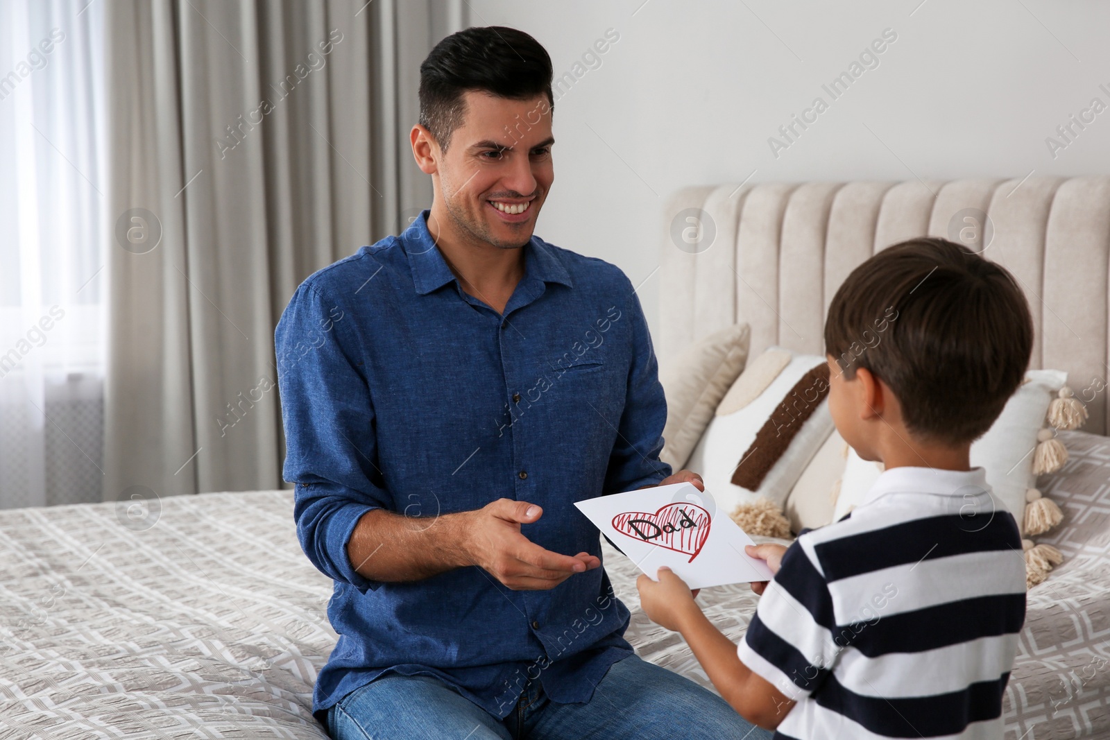 Photo of Little boy greeting his dad with Father's Day at home