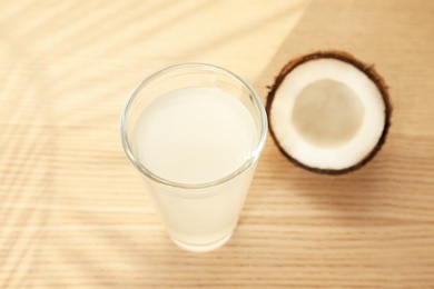 Photo of Glass with coconut water and fresh nut on wooden background