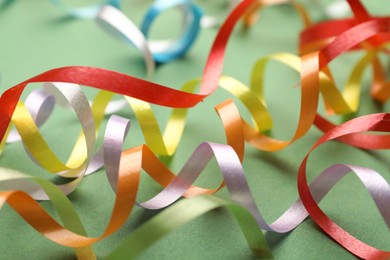 Colorful serpentine streamers on green background, closeup