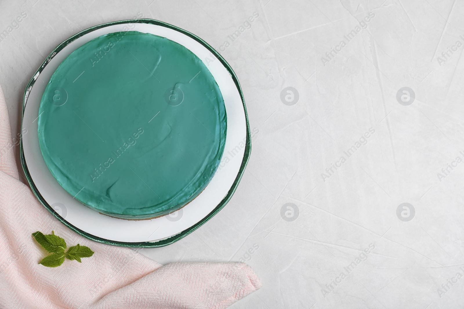 Photo of Delicious homemade spirulina cheesecake served on light background, top view. Space for text