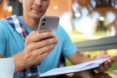 Photo of Man with smartphone working in outdoor cafe, closeup