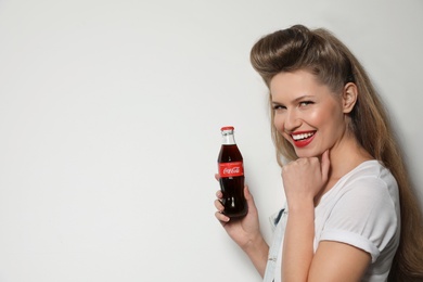 MYKOLAIV, UKRAINE - NOVEMBER 28, 2018: Young woman with bottle of Coca-Cola on white background, space for text