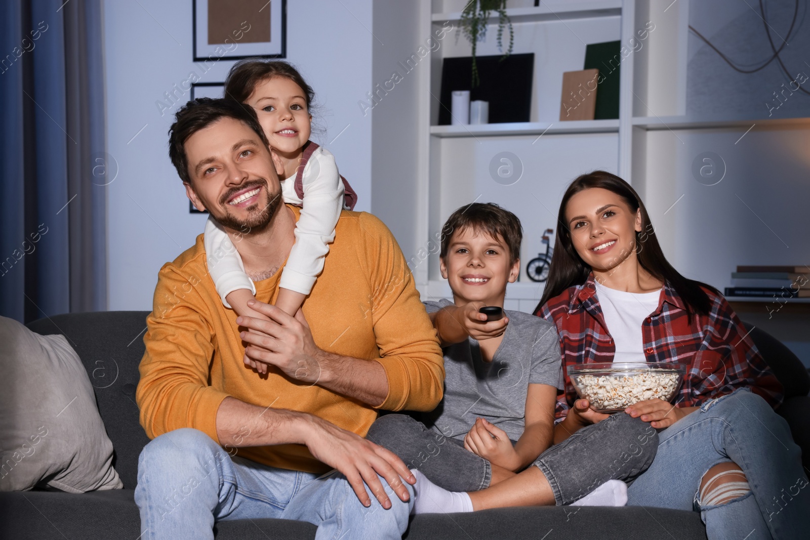 Photo of Happy family watching TV at home in evening