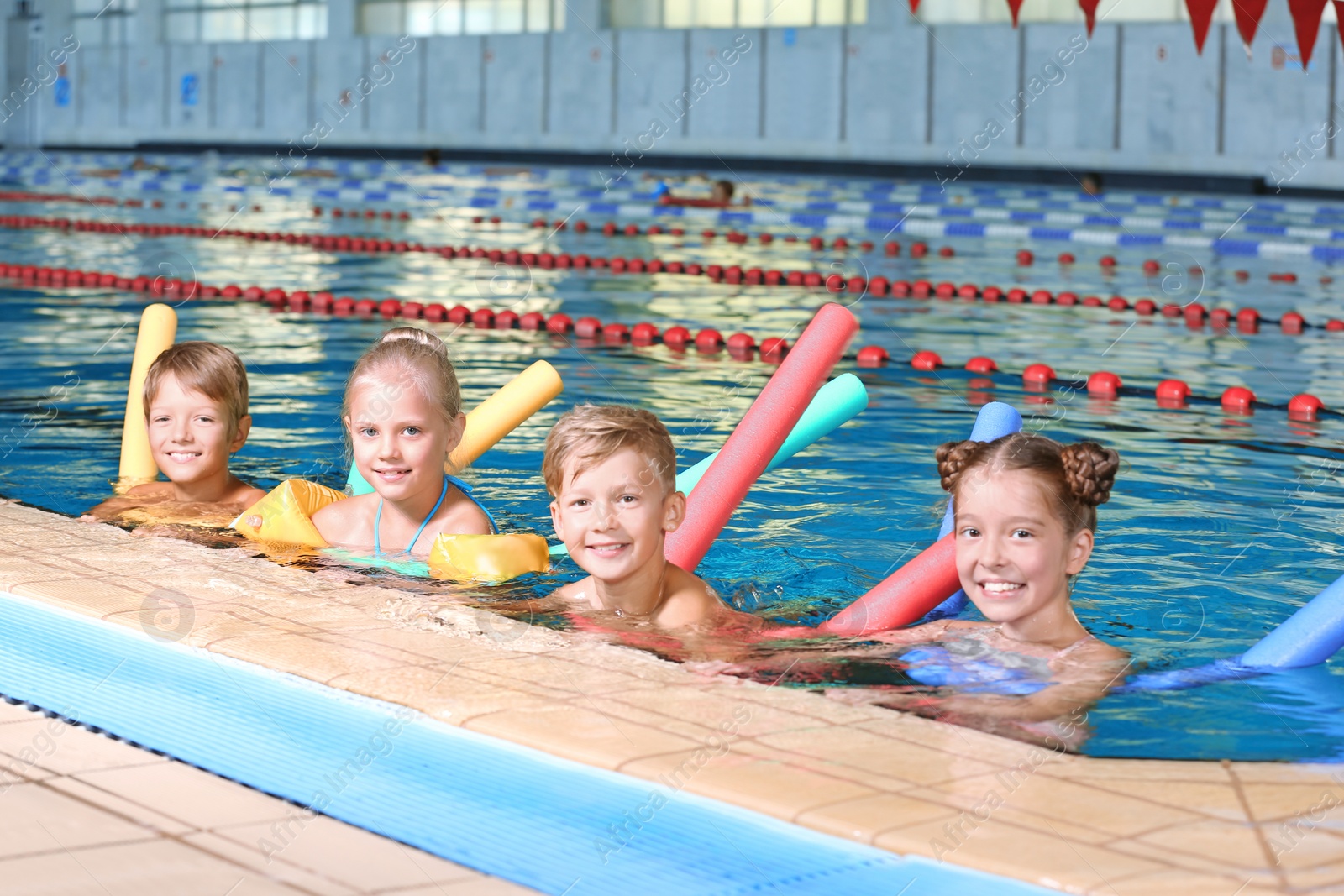 Photo of Little kids with swimming noodles in indoor pool