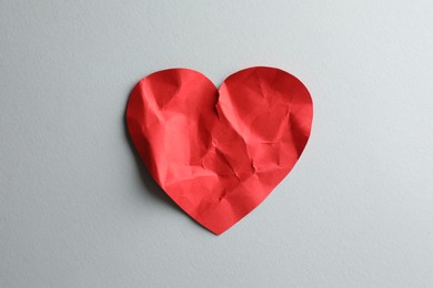 Photo of Crumpled red paper heart on white background, top view. Broken heart