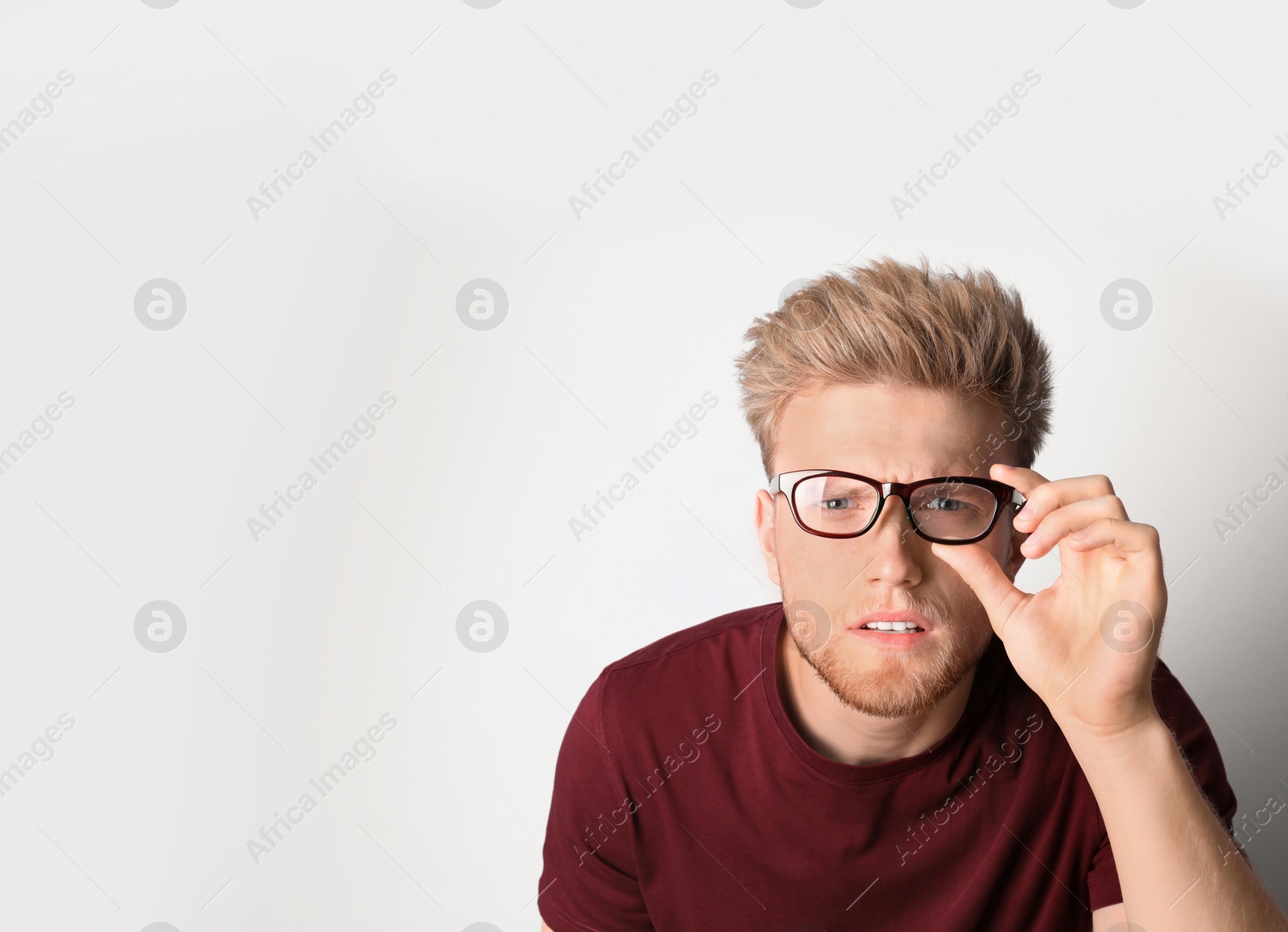 Photo of Young man with vision problem wearing glasses on light background