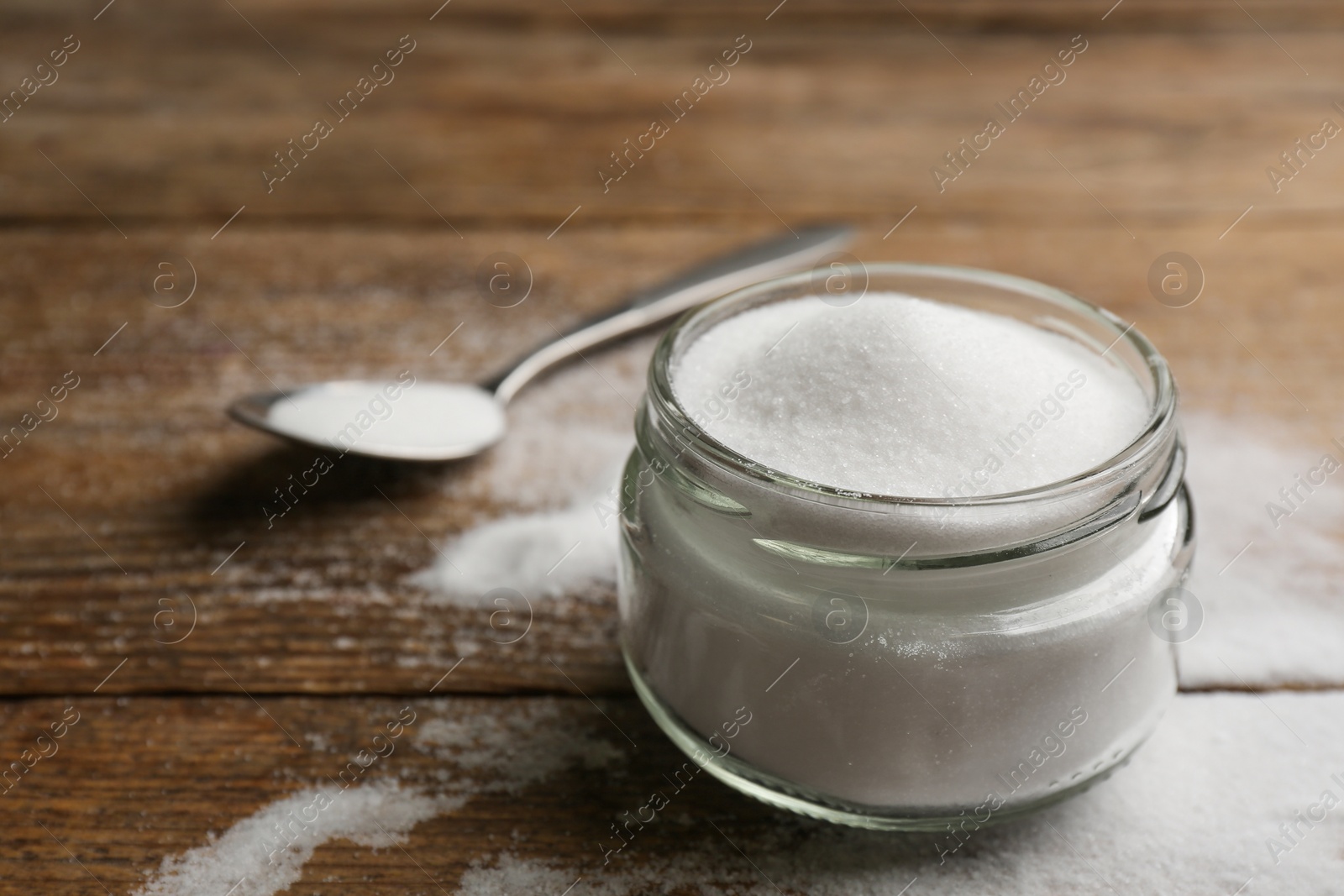Photo of Glass jar with salt on wooden table, closeup