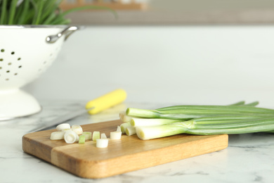 Photo of Fresh green spring onions on white marble table