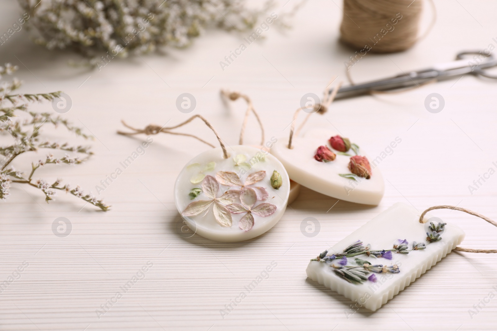 Photo of Scented sachets and flowers on white wooden table