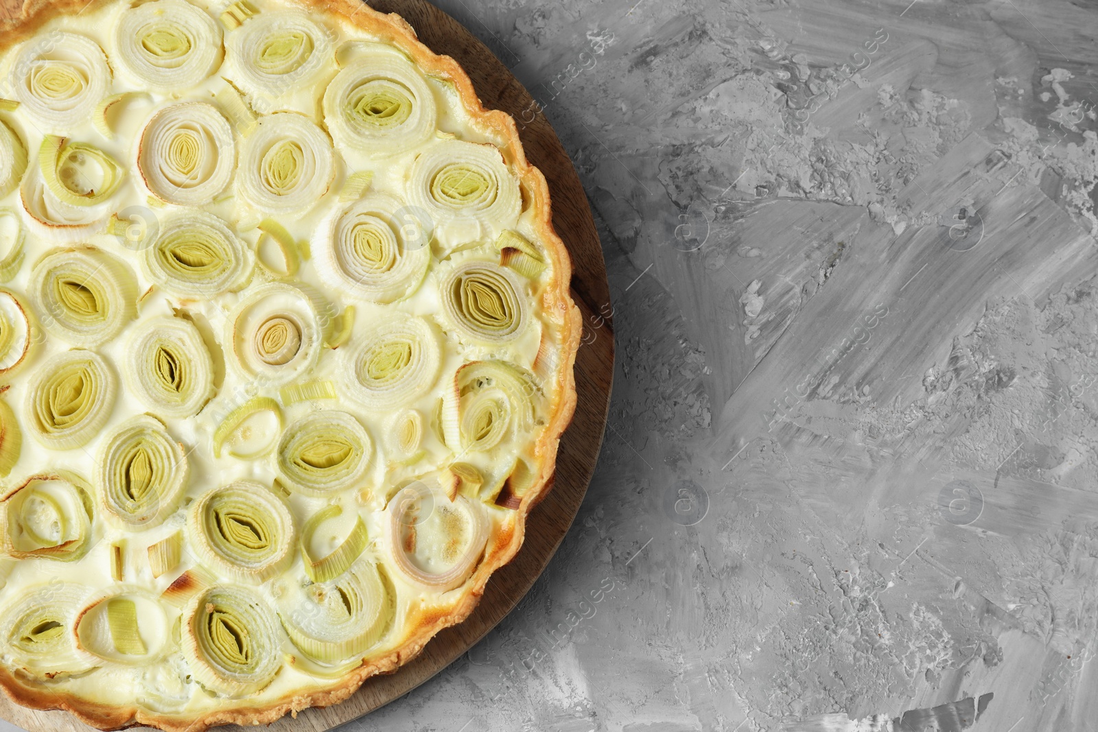 Photo of Freshly baked leek pie on grey textured table, top view. Space for text
