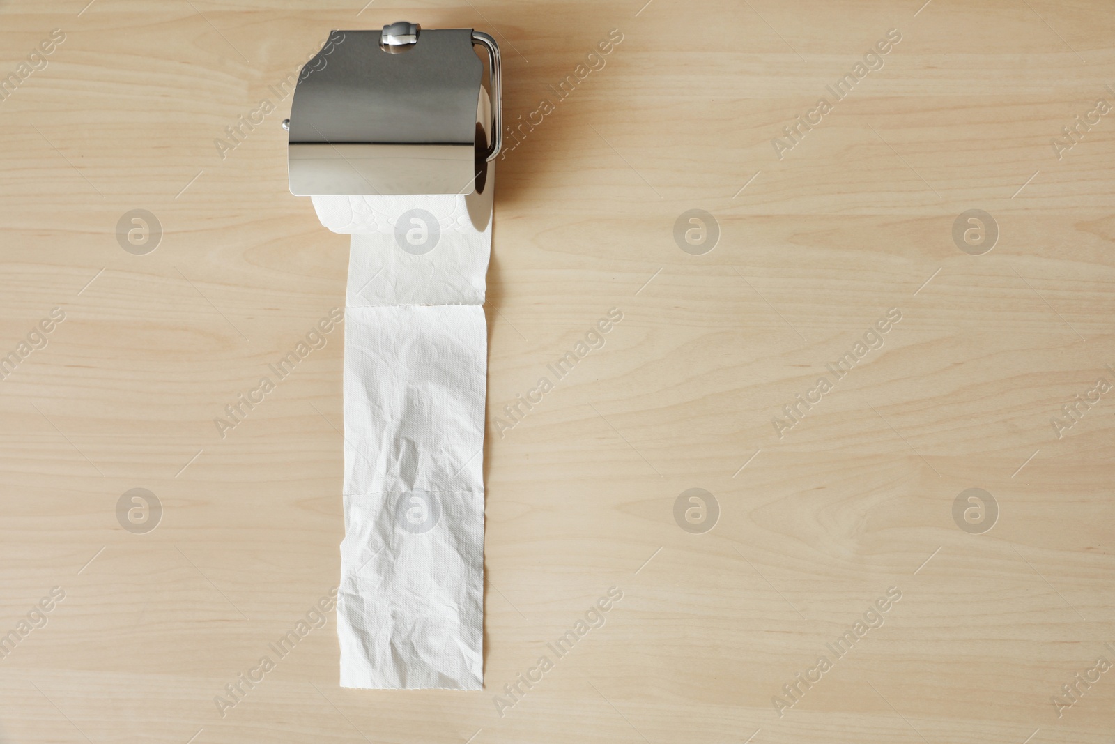 Photo of Holder with toilet paper roll on wooden background. Space for text