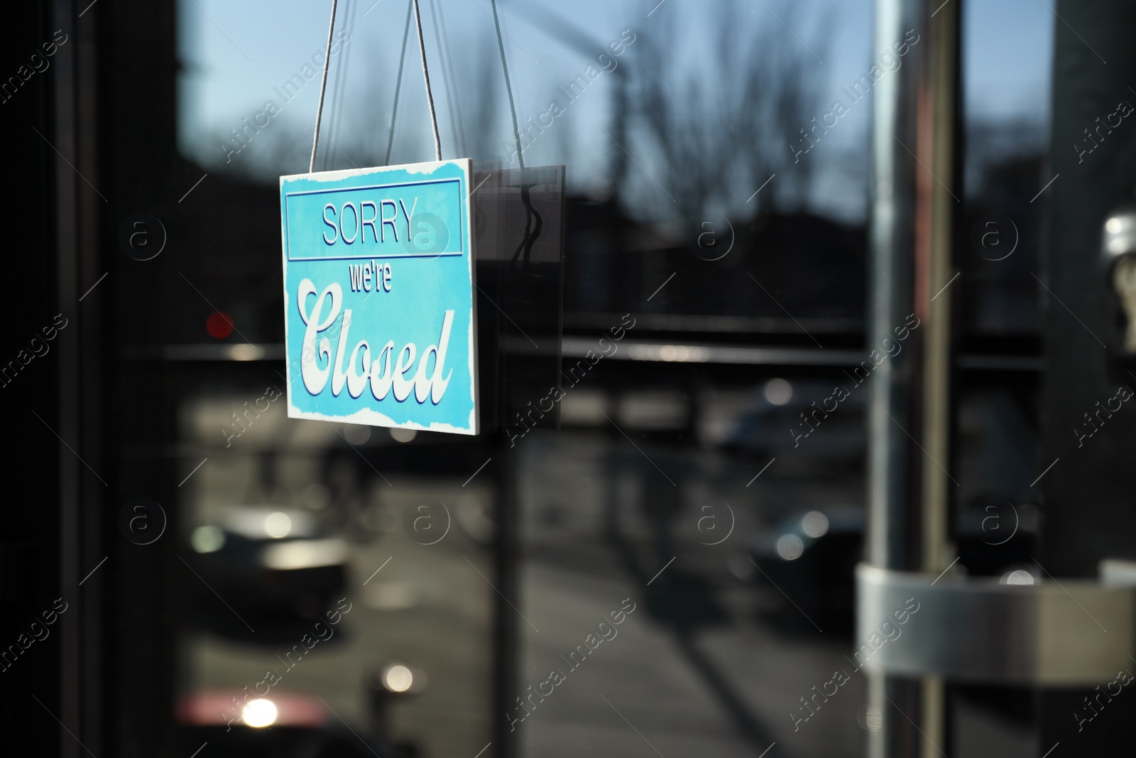 Photo of Light blue sign with text Sorry we're Closed hanging on glass door. Coronavirus quarantine