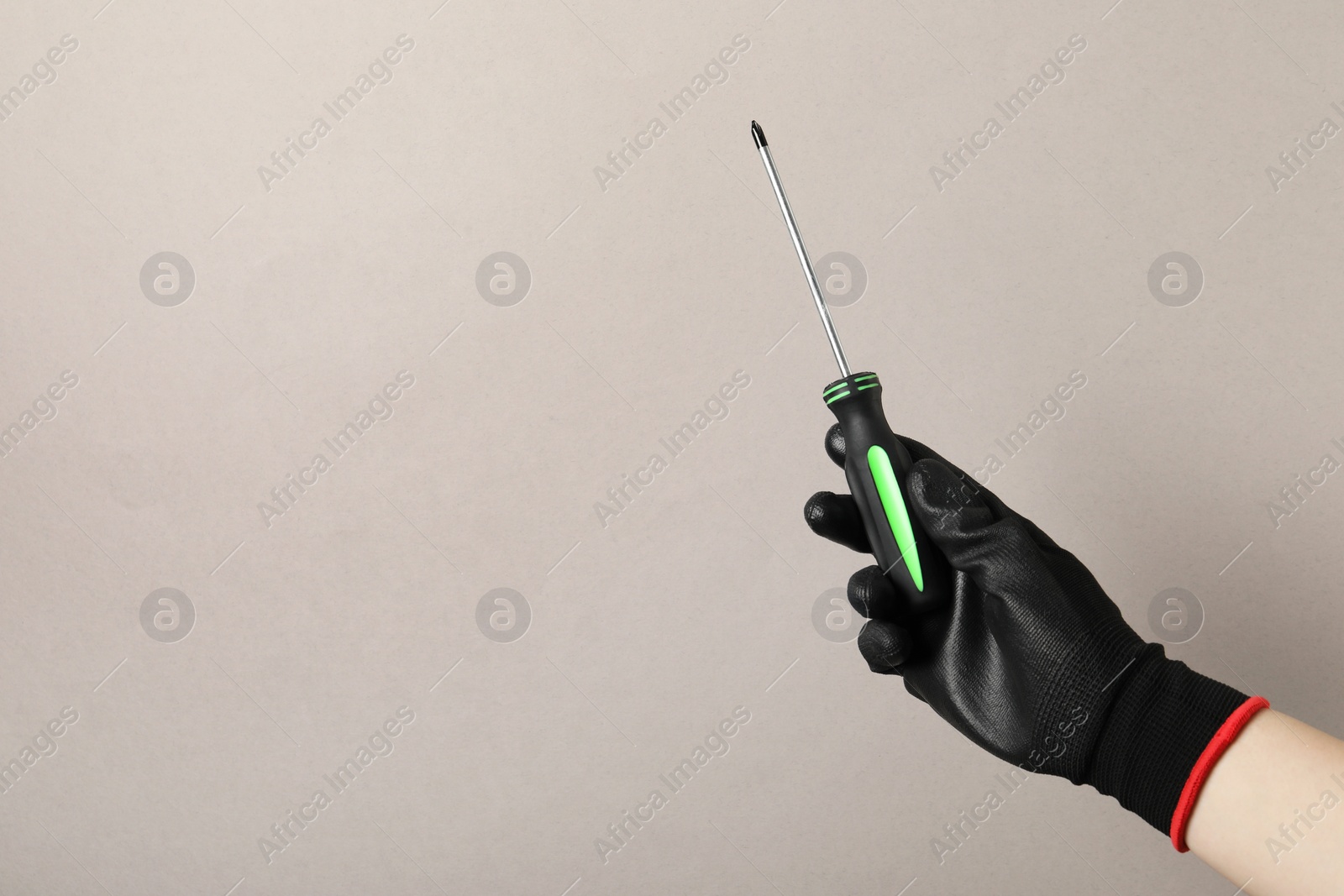 Photo of Woman holding screwdriver on grey background, closeup. Space for text