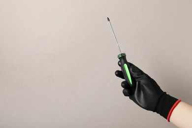 Photo of Woman holding screwdriver on grey background, closeup. Space for text