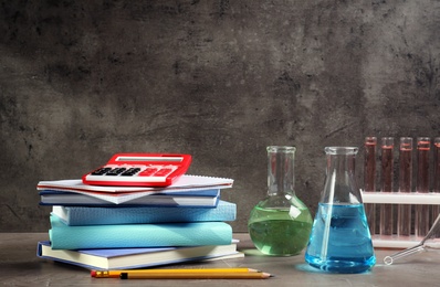 Photo of Laboratory glassware and stationery on table against grey background, space for text. Chemistry concept